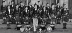 The band from 1952 outside Clyde St School, Helensburgh showing off their trophy haul. Back: Jimmy Simpson, Ian Lawrie, Dougie Martin, Tommy Williams, Malcolm Gilmour (remained with the band until 2015), Mick Thrule, Jimmy Martin; front: Pipe Major Archie McNicol, John Cameron, Robert Toole, Andy Clark, Tom McDougall, Jim Gunn (still the drumming instructor to this day). Info provided by Helensburgh Heritage Trust.